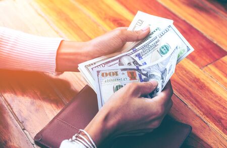Woman hands take US dollar banknotes from the purse.の写真素材
