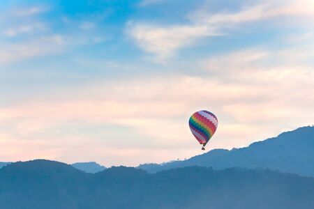 Colorful hot air balloon over sunrise with mountain view and fog in morningの写真素材