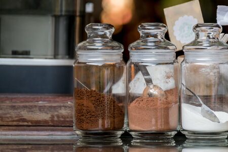 Three bottles of coffee cocoa and creamer on mirror-top wood tableの写真素材