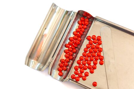 Red pills on stainless steel counting tray on white backgroundの写真素材