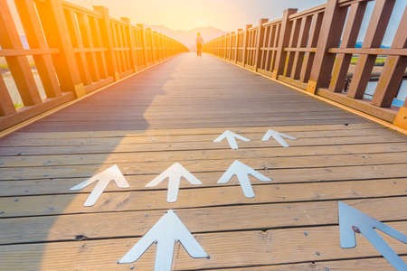 Arrow sign and wood walkwayの写真素材