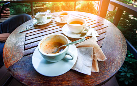 Cup of coffee on old wooden table with teaの写真素材