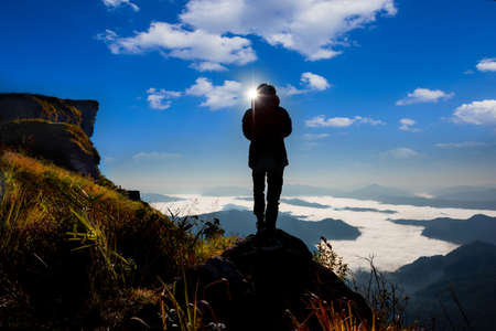 Male tourists stand to take pictures on rock at Phu chi fa,Chaingrai,Thailandの写真素材