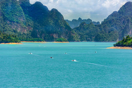 Tourists ride a long tail boat with beautiful nature mountain background, Ratchaprapa Dam and Cheow...