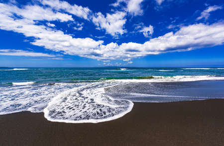 Tropical unusual exotic beach with black volcanic sand, blue sky with clouds. Kusamba beach, Bali, Indonesiaの写真素材