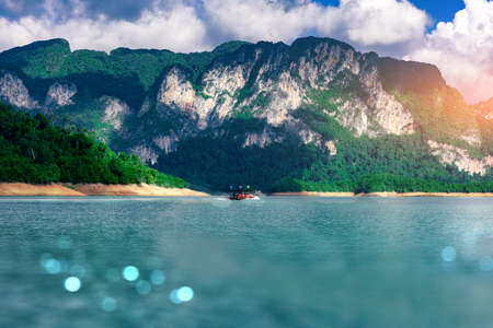 Tourists take a boat to see the beauty of the limestone mountains in the Ratchaprapa Dam in Thailandの写真素材