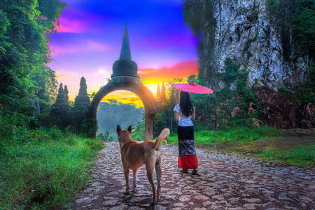 Thai woman hold red umbrellas with arch at Khao Na Nai Luang Dharma Park in Surat Thani Thailandの写真素材