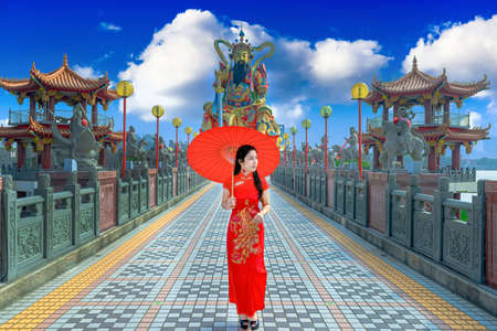 Beautiful women wearing dresses red cheongsam holding an umbrella walking on the bridge at Zuoying Yuandi temple,Taiwanの写真素材