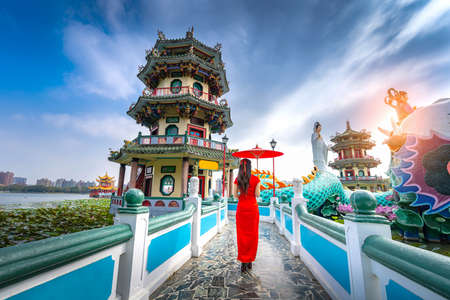 Asian  Woman Wearing Cheongsam Traditional Red Dress standing on bridge at Wuliting pavilion,Kaohsiung,Taiwanの写真素材