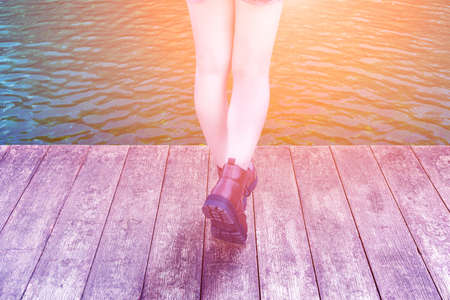 Woman step on wood pier at the riverside in the sunset time