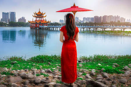 Beautiful Asian Woman Wearing Cheongsam, Traditional Red Dress, Standing to See the Wuliting Pavilion, Kaohsiung, Taiwanの写真素材