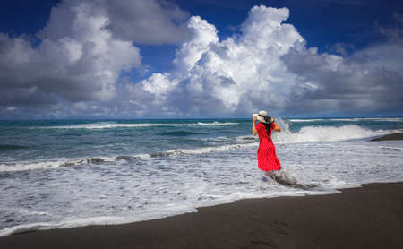 Woman standing on black sand beach in Padangbai, Bali Island, Indonesiaの写真素材