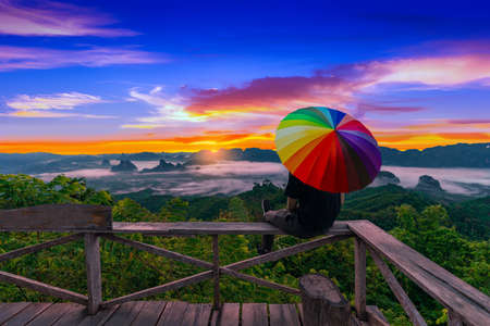 Male tourists watch the beautiful scenery during the sunrise of the Doi Ta Pang viewpoint. At Khao Talu Subdistrict, Sawi District, Chumphon Province in Thailand.の写真素材