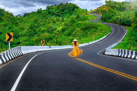 Asian tourist woman walking alone on country road rear view. Number three of road among the...