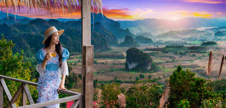 Woman drinking tea while enjoying a view of Phu Lang Ka in the morning in Phayao Province, Thailandの写真素材