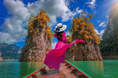 Beautiful girl standing on the boat and feel happy at Ratchaprapa Dam, Khao Sok National Park, Surat Thani Province, Thailandの写真素材