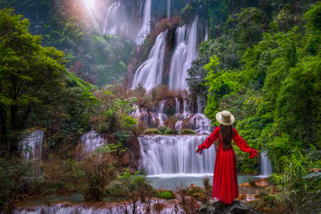 Asian woman standing on the rock at Tee lor su waterfall in Thailand at the tropical forest , Umphang District, Tak Province, Thailandの写真素材