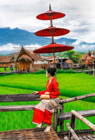 Thai women dressed in Thai Lanna costumes sitting in front of important tourist sites in Nan province, Thailand.Thai translation:Welcomeの写真素材