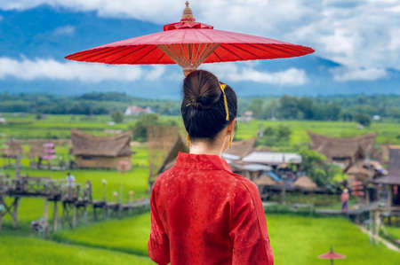 Behind a Thai woman dressed in Thai costumes stands holding an umbrella to see popular tourist attractions in Nan Province, Thailand.の写真素材