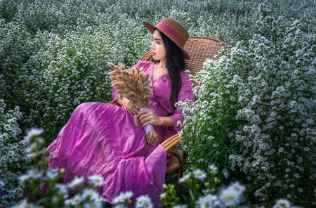 Beautiful Thai woman sitting among white cutters fields in Chiang Mai, Thailandの写真素材