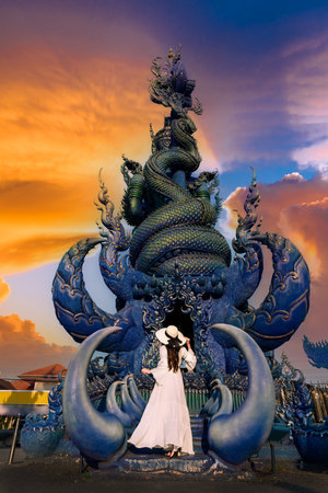 Asian woman tourists stand to admire a blue statue in a temple in Chiang Rai, Thailandの写真素材