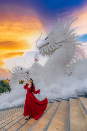 Asian woman in red dress visit famous temple at sunset in Chiang rai province, Thailandの写真素材