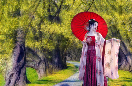 Asian women dressed in Chinese costumes standing in the yellow flower tunnelの写真素材