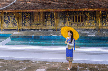 Asian woman wearing a Lao national costume visits Wat Xieng Thong in Luang Prabang, Laosの写真素材