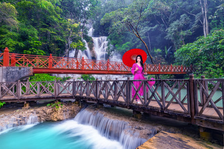 Young Asian woman in pink dress walking on wooden path in Kuang Si waterfall the most popular tourist attractions Lungprabang, Laosの写真素材