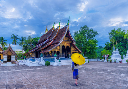 Asian woman wearing a Lao national costume visits Wat Xieng Thong in Luang Prabang, Laosの写真素材