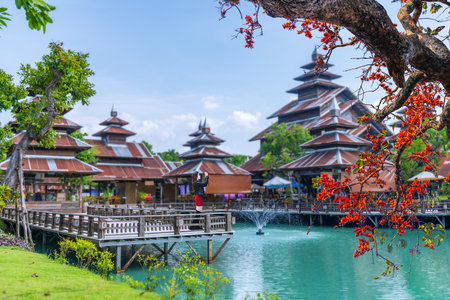 Young Asian woman visits an ancient wooden building with a colorful tin roof in Sakon Nakhon Province, Thailandの写真素材