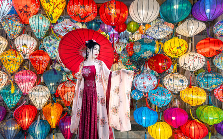 Young Asian tourist in a cheongsam poses with lanterns in Hoi An, Vietnamの写真素材