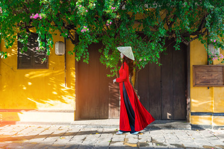 Young Vietnam woman wearing Ao Dai culture traditional walking on local street at Hoi an, Vietnamの写真素材