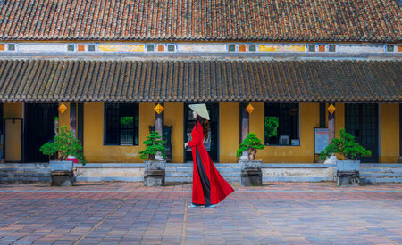 Asian woman in ao dai dress visits the Royal Palace of the Nguyen Dynasty in Hue, Vietnam