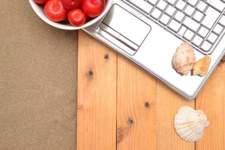 Laptop, plums and shells on wood and sandの写真素材