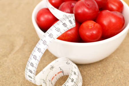 Red plums and tape measureの写真素材