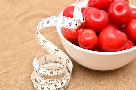Red plums and tape measureの写真素材