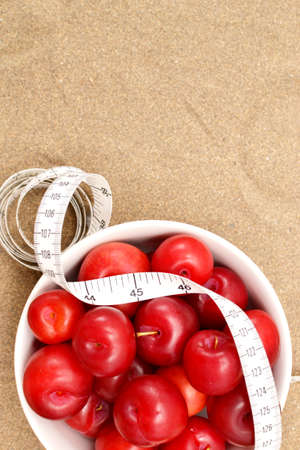 Red plums and tape measureの写真素材
