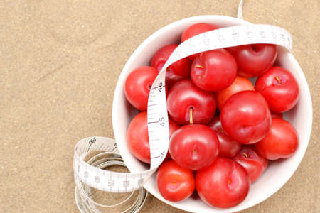 Red plums and tape measureの写真素材