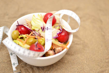 salad and tape measure on sandの写真素材