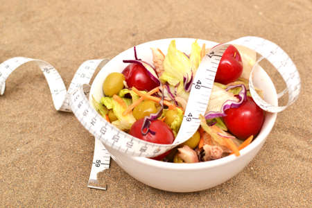 salad and tape measure on sandの写真素材
