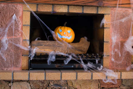 Halloween pumpkin and spider web in a fireplaceの写真素材