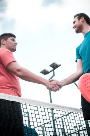 Friends shaking hands in paddle tennisの写真素材