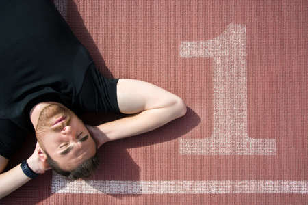 Man lying on the running trackの写真素材