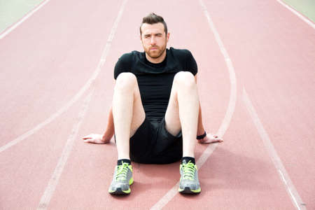 Man sitting on the running trackの写真素材