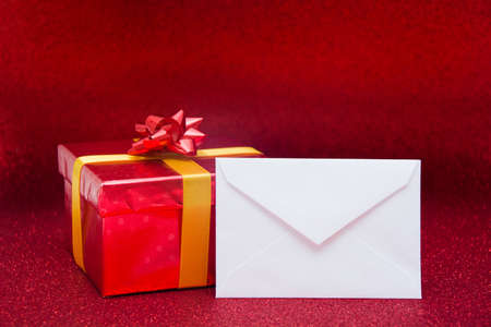 Red gift box and envelope with red backgroundの写真素材