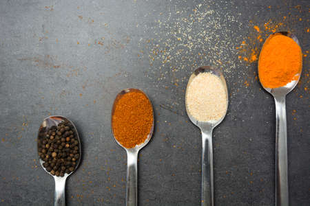 Spoons with spices on slate tableの写真素材
