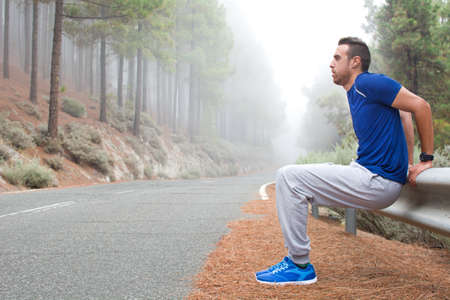 Young man exercising on the road with winter landscape background