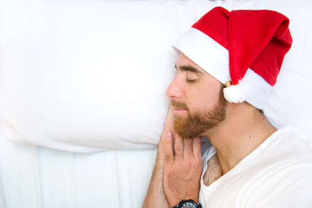 Man with santa hat sleeping in bedの写真素材