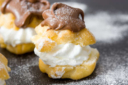 Fresh profiteroles with cream and chocolate frosting on slate